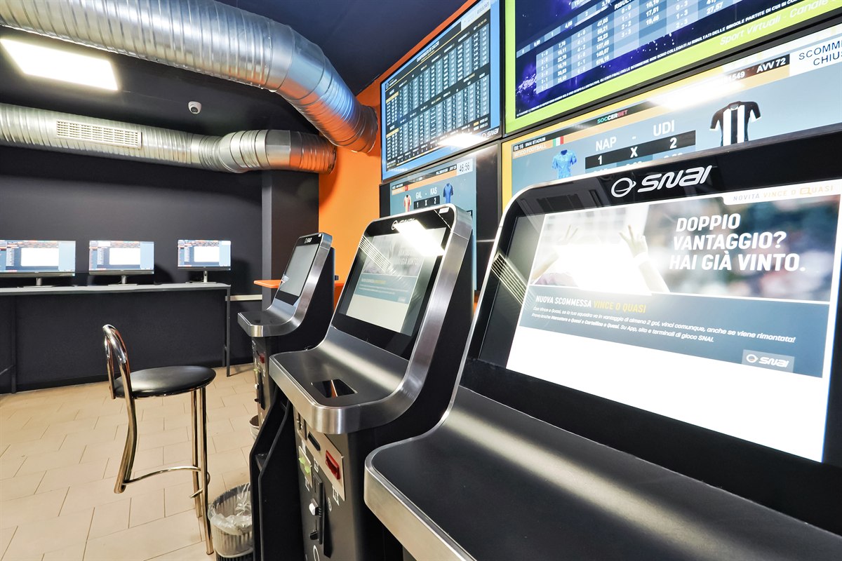 Interno agenzia scommesse con schermi sportivi
