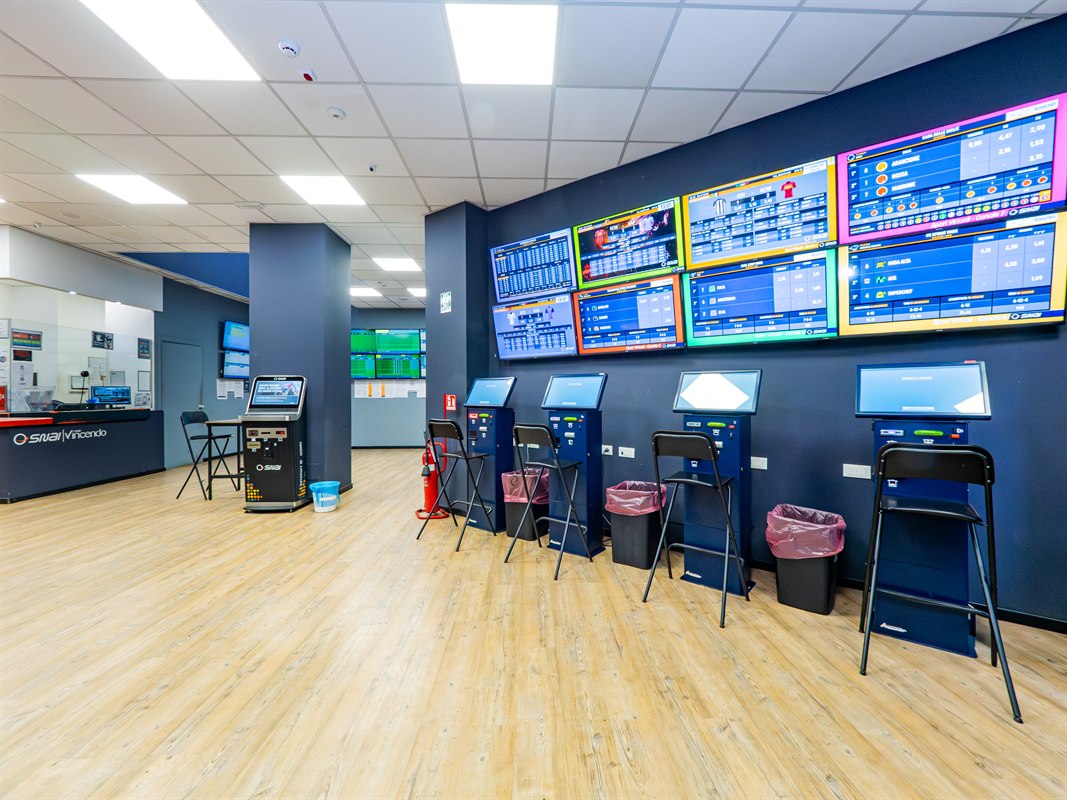 Interno agenzia scommesse con schermi sportivi