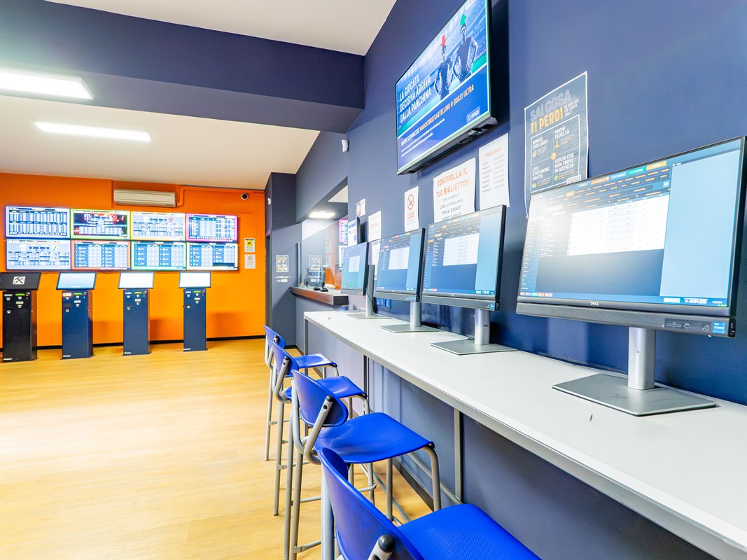 Interno agenzia scommesse con schermi sportivi