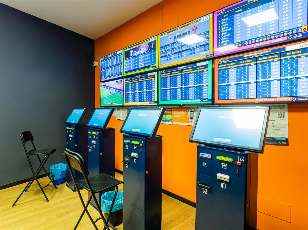 Interno agenzia scommesse con schermi sportivi