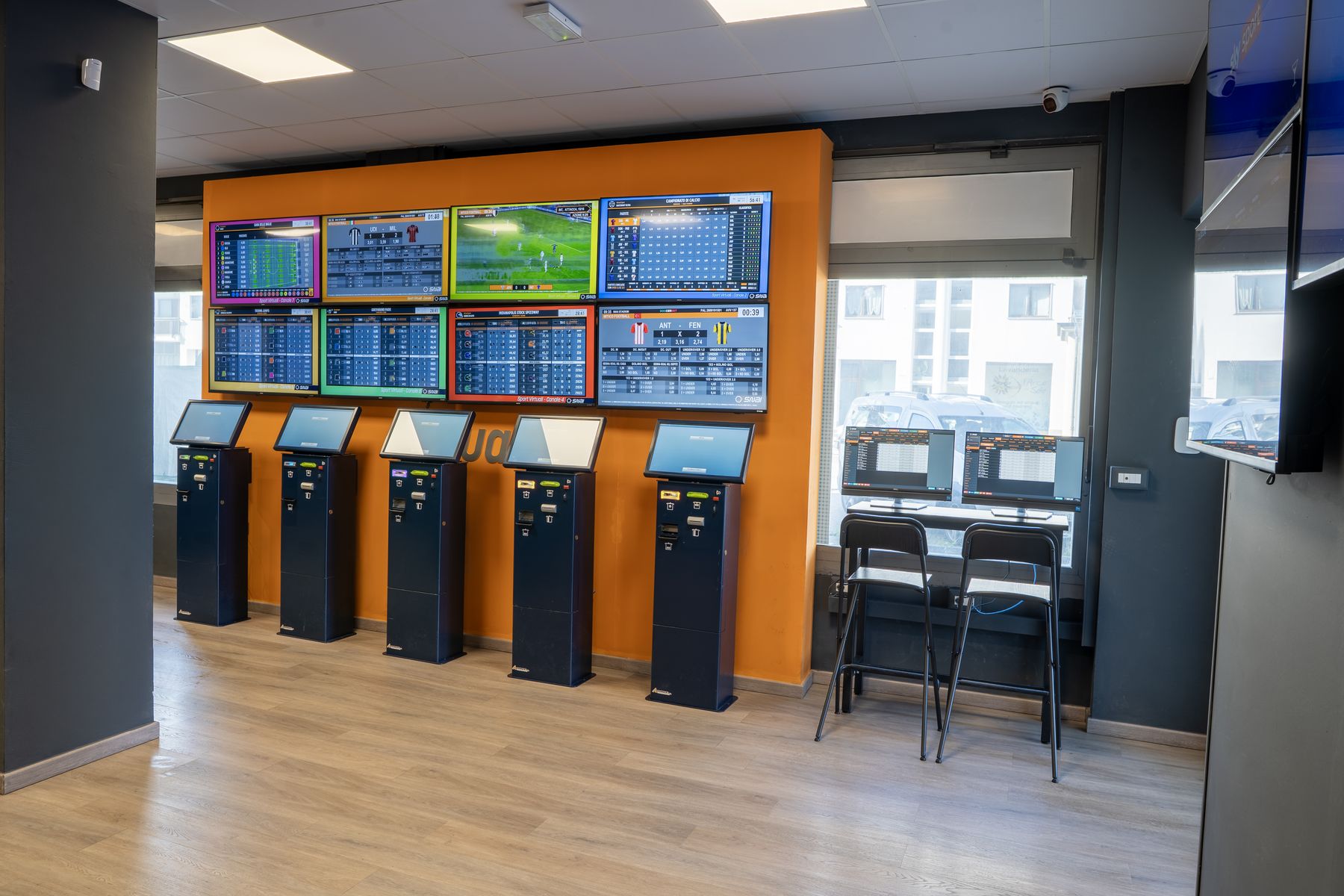 Interno agenzia scommesse con schermi sportivi