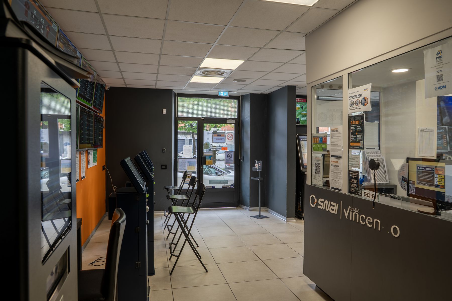 Interno agenzia scommesse con schermi sportivi