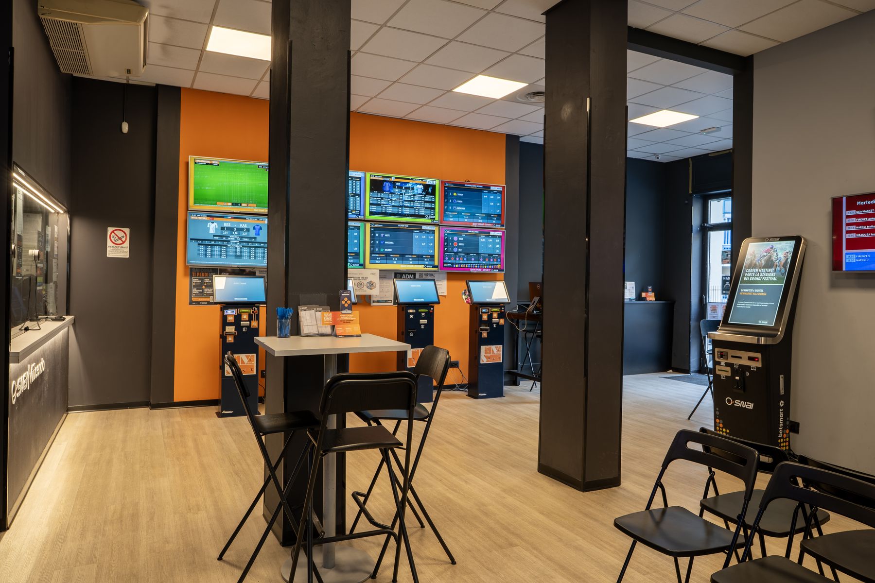 Interno agenzia scommesse con schermi sportivi