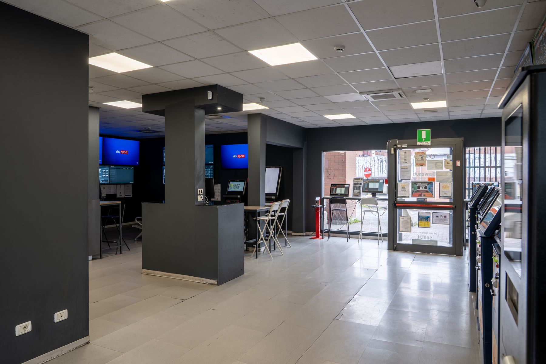Interno agenzia scommesse con schermi sportivi