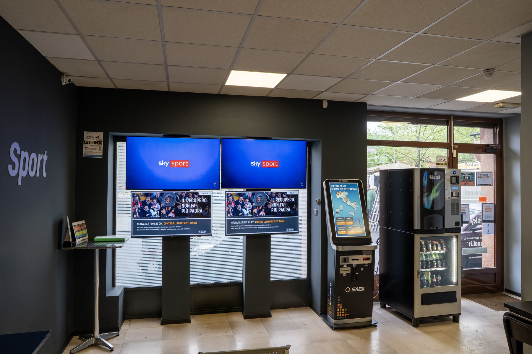 Interno agenzia scommesse con schermi sportivi