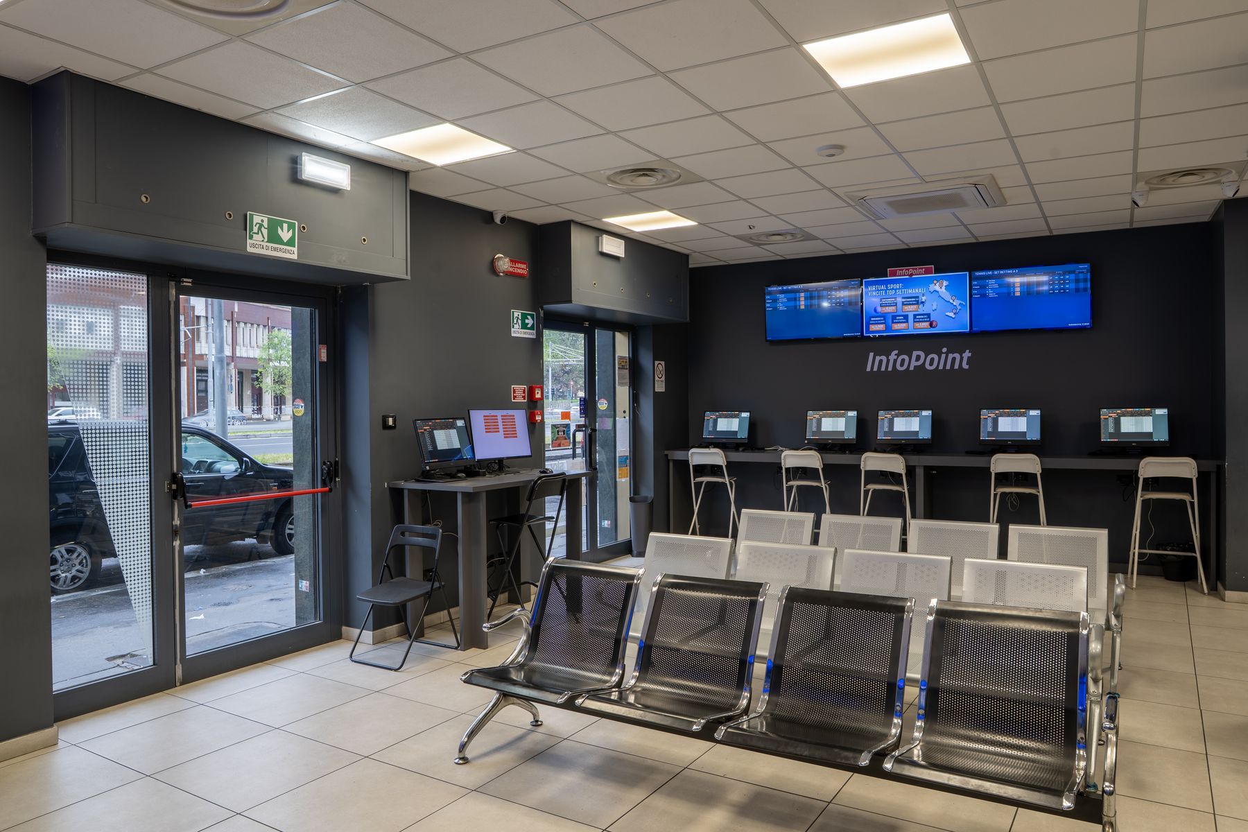 Interno agenzia scommesse con schermi sportivi